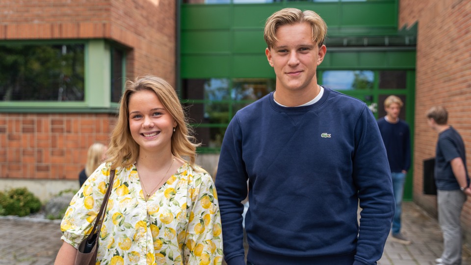 En tjej och en kille hänger på skolgården, fler elever anas längre bort 